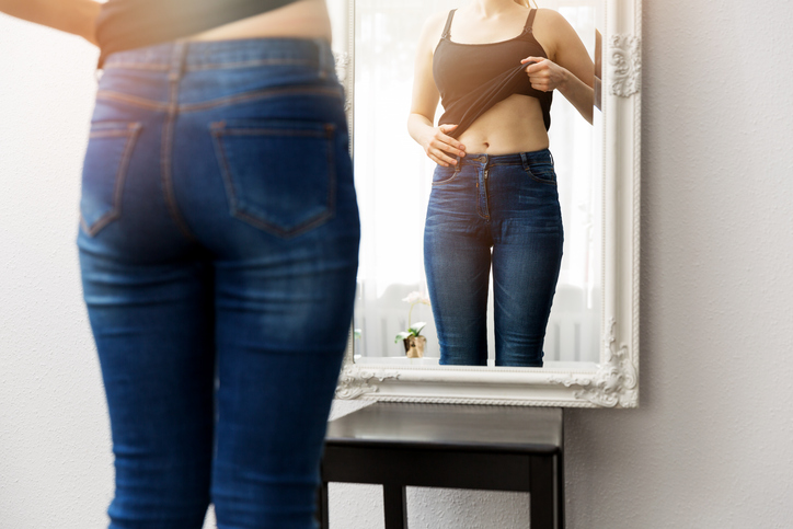 Woman checking her stomach in front of mirror