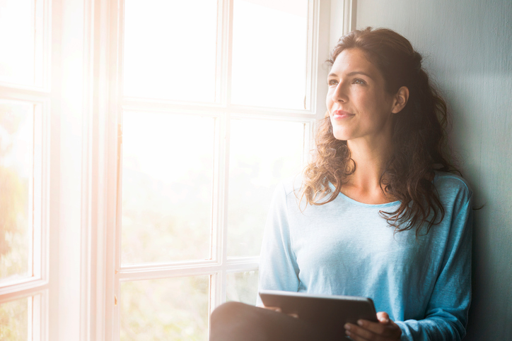 Thoughtful young woman looking out the window reflecting on her inner dialogues to build self awareness